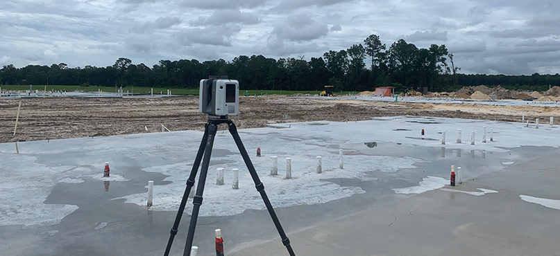Laser scanner on a tripod scans a concrete slab on a large construction site 