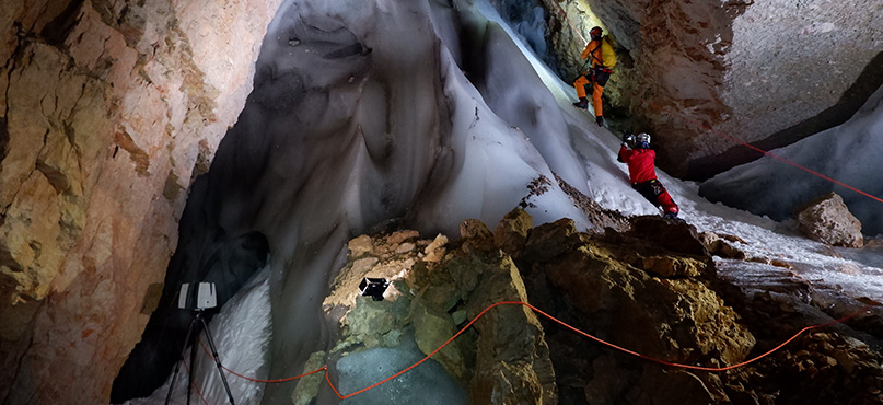 Surveyors using a 3D laser scanner to capture measurements in an ice cave in Italy