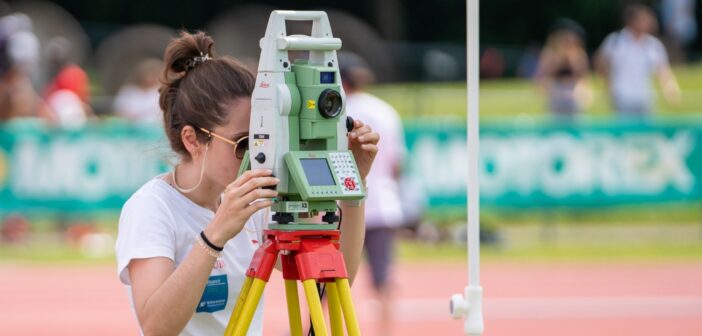 Woman uses a total station to measure distances at a track and field event